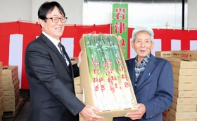 岩津ねぎ部会の荒川欣也部会長（右）から、ＪＡたじまの役員に丹精したネギが手渡された＝朝来市和田山町枚田