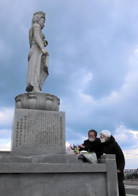慰霊碑の観音菩薩（ぼさつ）像に花を手向ける藤崎光子さん＝香美町香住区余部