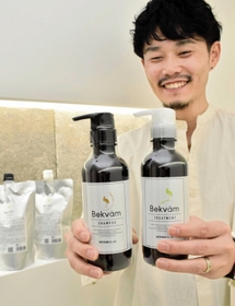 コウノトリ育むお米の米ぬかを配合したシャンプーとトリートメントを手にする本山隆幸社長＝豊岡市千代田町
