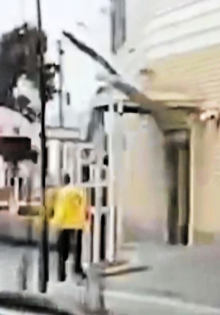 ドライブレコーダーに写っていた外壁が崩落する瞬間。黄色の上着を着た係員の上に落下物が写っている＝豊岡市大手町（読者提供）