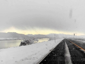 降雪があった昨年１２月１８日に、車から見た豊岡市内の空模様。にび色の雪雲に覆われるが、奥（内陸部）の出石・日高方面には青空が広がる（助手席から撮影）