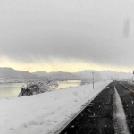 降雪があった昨年１２月１８日に、車から見た豊岡市内の空模様。にび色の雪雲に覆われるが、奥（内陸部）の出石・日高方面には青空が広がる（助手席から撮影）