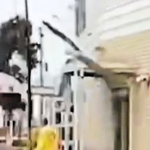 ドライブレコーダーに写っていた外壁が崩落する瞬間。黄色の上着を着た係員の上に落下物が写っている＝豊岡市大手町（読者提供）