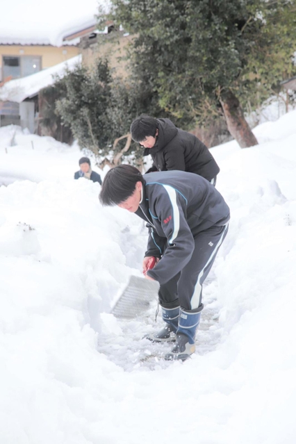 公会堂までの上り坂に積もった雪を取り除く生徒たち＝香美町村岡区板仕野