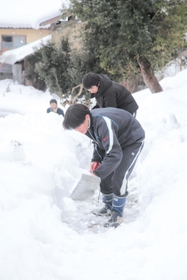 公会堂までの上り坂に積もった雪を取り除く生徒たち＝香美町村岡区板仕野