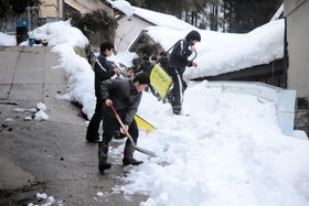 公会堂までの上り坂に積もった雪を取り除く生徒たち＝香美町村岡区板仕野