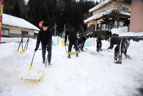 防火水槽の上に積もった雪を運び出す生徒たち＝香美町村岡区板仕野