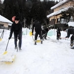 防火水槽の上に積もった雪を運び出す生徒たち＝香美町村岡区板仕野