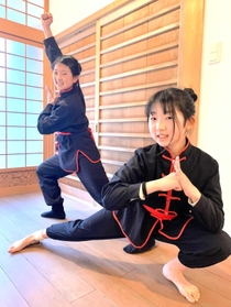 カンフーのポーズをとる小原百恵さん（左）と、妹の恵子さん＝豊岡市出石町