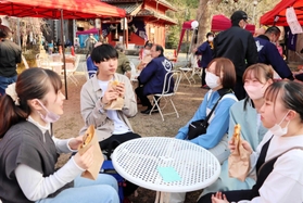 露店で購入した飲食物を楽しむ大学生ら＝豊岡市京町、本町稲荷神社