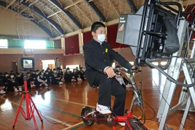 同級生が見守る中、自転車シミュレーターで運転する生徒＝浜坂中学校