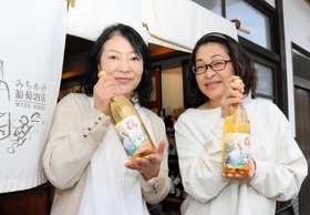 豊岡市産ブドウを使った白ワイン「こうのとりわいん」のラベルを手がけた河合美智子さん（右）、成相淑子さん＝豊岡市出石町魚屋