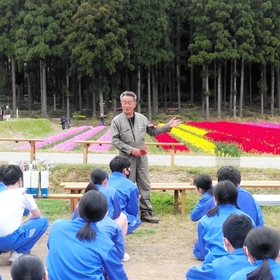 但東中学校の生徒に語りかける「たんとうチューリップまつり」の実行委員長、霜倉和典さん（河合美智子さん撮影）