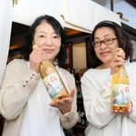 豊岡市産ブドウを使った白ワイン「こうのとりわいん」のラベルを手がけた河合美智子さん（右）、成相淑子さん＝豊岡市出石町魚屋