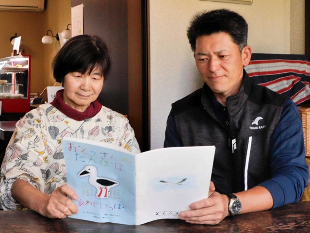絵本を読む青山直也さん（右）と川田恵美子さん＝豊岡市日高町万劫