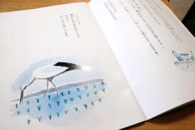 青山さんの田んぼに降りて餌をついばむコウノトリを描いた絵本の一場面＝豊岡市日高町万劫