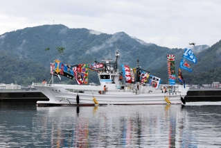 色鮮やかな大漁旗をなびかせて入港する「大祐丸」＝香住漁港西港