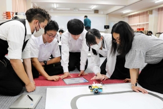 ネーティブ教員やＡＬＴらとロボットプログラミングを学ぶ高校生たち＝豊岡高校