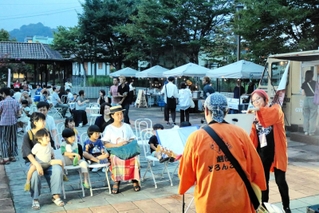「豊岡演劇祭２０２３」の出演者や観客、地元住民らが交流する「ナイトマーケット」が１６日夜、ＪＲ江原駅前イベント広場（豊岡市日高町日置）で始まった。前半の同日と１７日は、豊岡市内などの飲食店や農家らがブースを出し、縁日のようなにぎわいを見せた。（阿部江利）