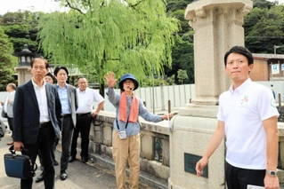 北但大震災当時の様子などの説明を聞きながら、まち歩きをする斎藤元彦知事（右）＝城崎温泉街