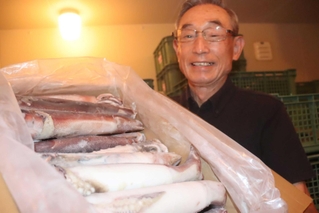 今年の「みほのうらいか糀」に使うスルメイカを掲げる御火浦村おこしグループ代表の脇本松夫さん＝新温泉町三尾
