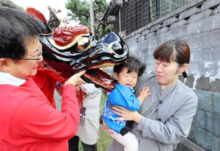 健やかな成長を願って子どもの頭をかむ麒麟獅子＝香美町香住区鎧