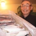 今年の「みほのうらいか糀」に使うスルメイカを掲げる御火浦村おこしグループ代表の脇本松夫さん＝新温泉町三尾
