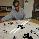 宮下家の船「明神丸」や「明生丸」の手ぬぐいを広げる仙之助さん。家訓の「早上下」が記されている＝香美町香住区香住