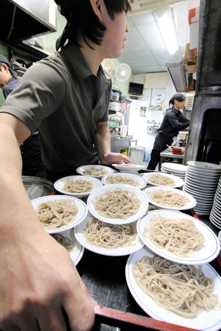 小皿に盛り付けられた出石そば。手際よく従業員が盛り付け、運んでいく＝豊岡市出石町小人
