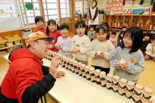 園児たちにノリのつくだ煮をプレゼントする「にしともかに市場」の山田直弘店長＝青葉保育園