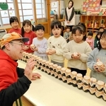 園児たちにノリのつくだ煮をプレゼントする「にしともかに市場」の山田直弘店長＝青葉保育園