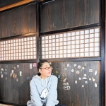 引っ越し先でお気に入りの建具の前に座る河合美智子さん＝豊岡市内（本人提供）
