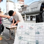 「豊岡復興建築群」に施された装飾のデザインスタンプを、オリジナルマップに押す参加者たち＝豊岡市中央町