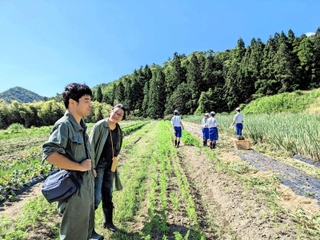 農作業を体験する中学生の近くで、小山収平さん（左）に話を聞く河合美智子さん＝豊岡市出石町