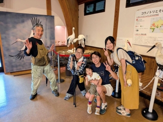 河合美智子さん（左から２人目）と記念撮影する理学療法士の一家＝豊岡市立コウノトリ文化館（河合さん提供）