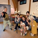河合美智子さん（左から２人目）と記念撮影する理学療法士の一家＝豊岡市立コウノトリ文化館（河合さん提供）