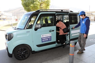 養父市のライドシェアサービス「やぶくる」の車に乗る利用者と、補助するドライバー＝養父市八鹿町八鹿（４月１日撮影）