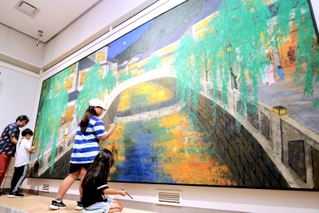 岩絵の具で色を付け足す子どもと、日本画家の山田毅さん（左）＝円山川公苑美術館