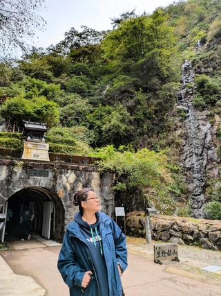 生野銀山の坑道前にたたずむ河合美智子さん