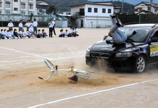 交通安全教室で自転車が絡む事故を再現するスタントマン＝梁瀬中学校