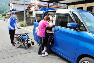 ヘルパーとともに利用者を車に乗せる手伝いをする「やぶくる」運転手の土居一雄さん（左）＝養父市大屋町中