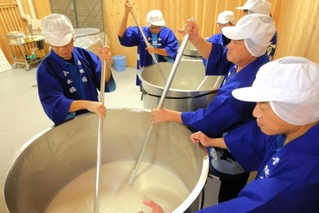 タンクの酒母をかき混ぜる蔵人たち＝香住鶴
