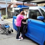 ヘルパーとともに利用者を車に乗せる手伝いをする「やぶくる」運転手の土居一雄さん（左）＝養父市大屋町中