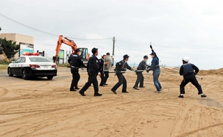 府県境をまたいだ逃走を想定した訓練で、一緒に犯人の確保に臨む豊岡署と京丹後署の警察官たち＝京都府京丹後市久美浜町