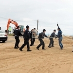 府県境をまたいだ逃走を想定した訓練で、一緒に犯人の確保に臨む豊岡署と京丹後署の警察官たち＝京都府京丹後市久美浜町