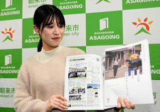 朝来市が作成した就活サポートブックとモデルを務めた入庁７年目の田路遥さん＝同市役所