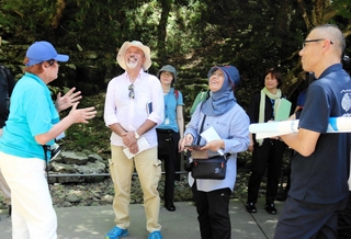 玄武洞公園を訪れ、取り組みについて説明を受ける審査員たち（前列左から２、３人目）＝２０２４年７月、豊岡市赤石