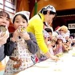 ２０メートルを超える長い巻きずしを切って食べる参加者たち＝中竹野ふるさと館