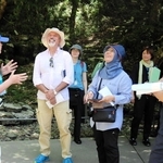 玄武洞公園を訪れ、取り組みについて説明を受ける審査員たち（前列左から２、３人目）＝２０２４年７月、豊岡市赤石