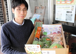 地元の生産者から届いた商品を手にする遠藤真森さん＝豊岡市中央町
